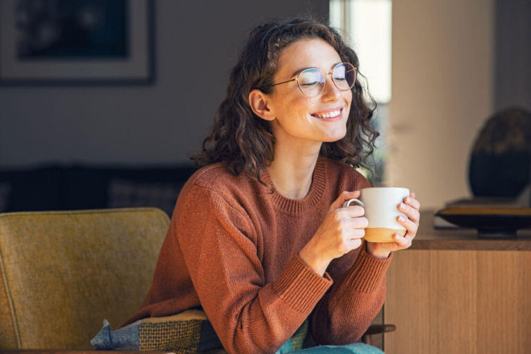 woman smiling holding a cup of coffee